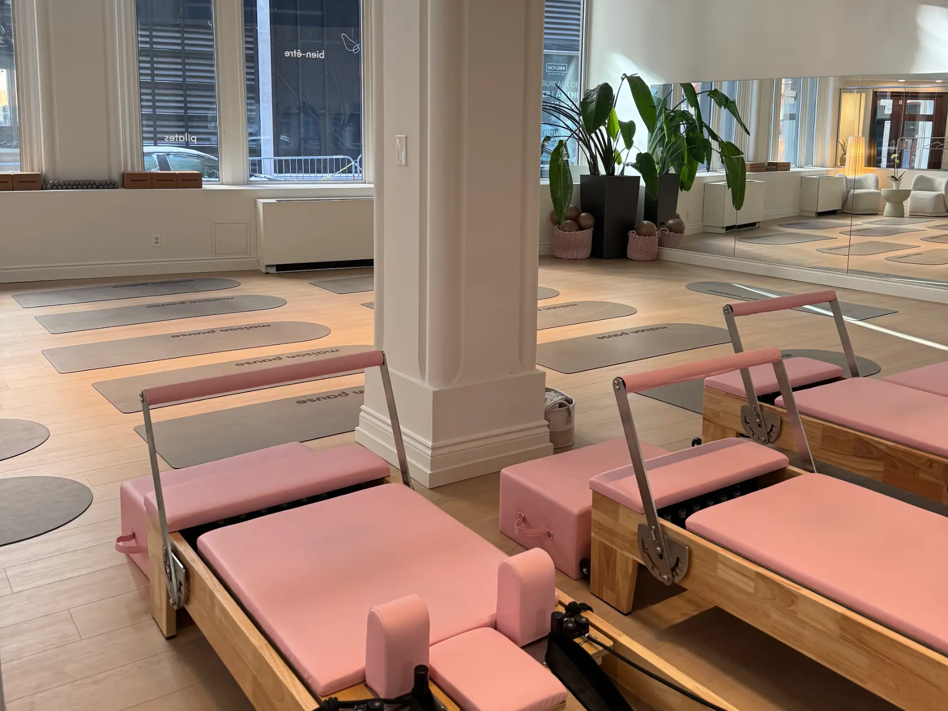 Maison Pause studio interior with pink reformers, branded mats, and arched mirrors